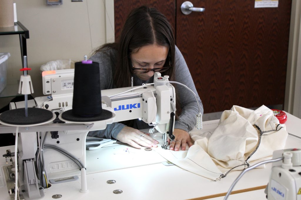 Student sews muslin garment.