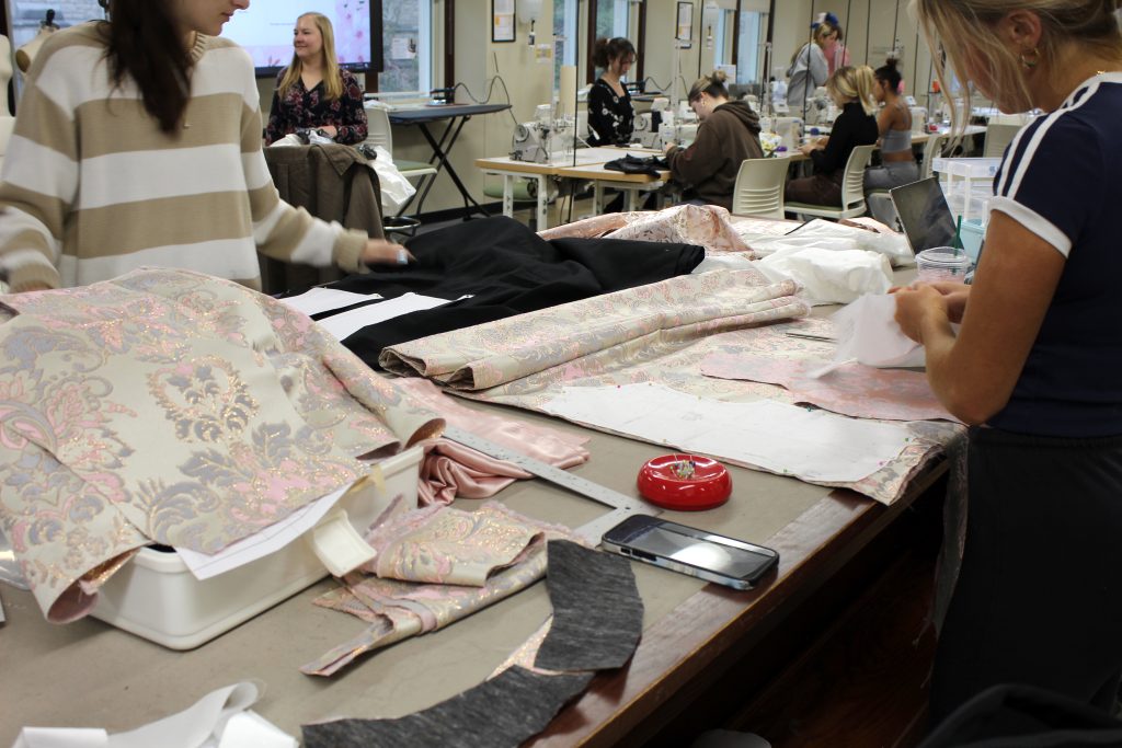 Students cut pattern pieces in fashion fabric.